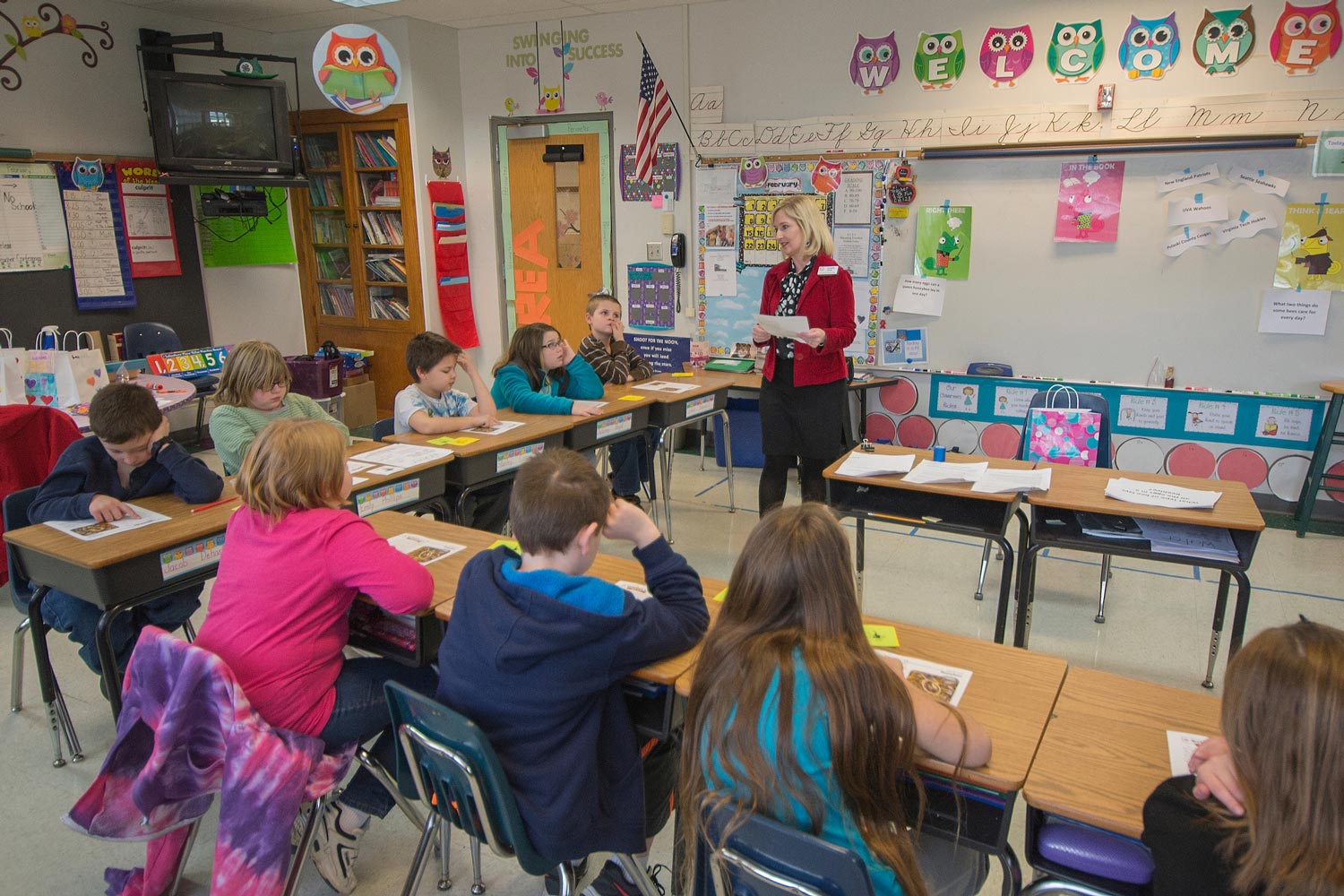 teacher in front of colorful classroom of children