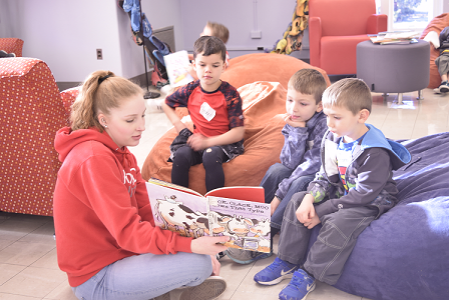 student in a classroom reading to children