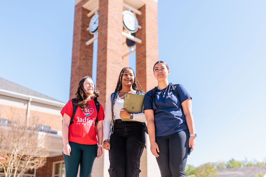 Three female students stand outside the Bonnie Student Center on a sunny day. 