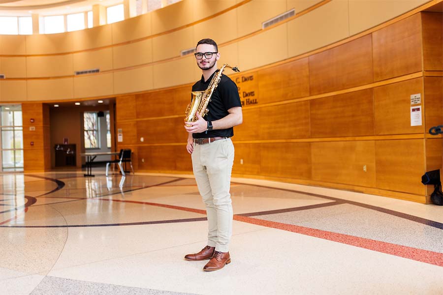 Student holding saxophone, standing in the lobby of Radford's Covington Center