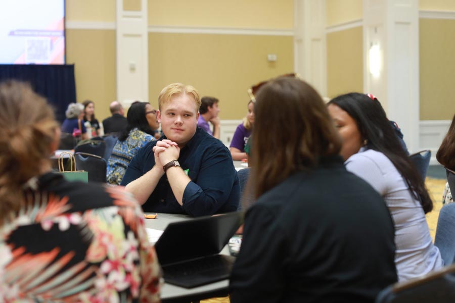 A student sits at a table with colleagues during a conference on voting.