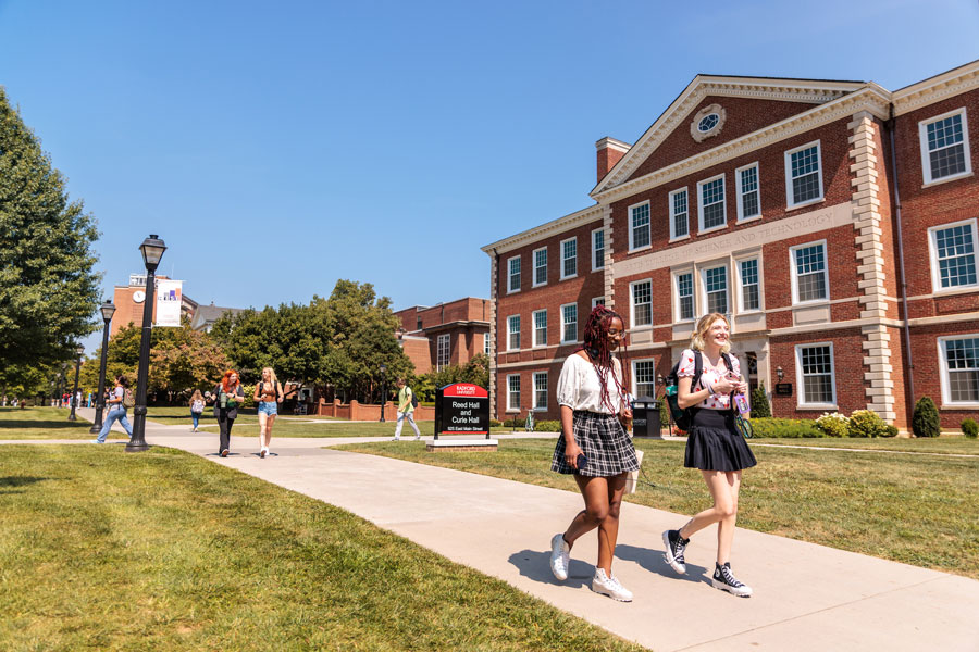 Students walking on sidewalk outside Reed Hall and Curie Hall.