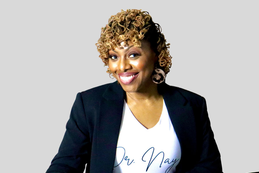 Nayshon Mosley-Milford sitting at a desk with a laptop and smiling, holding a pencil.