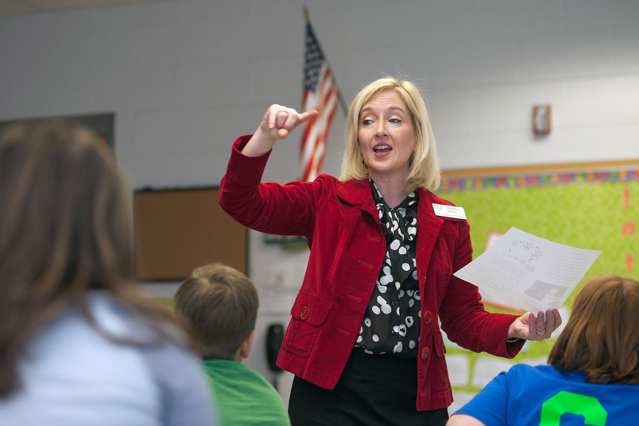 professor with blond hair and red blazer giving a lecture