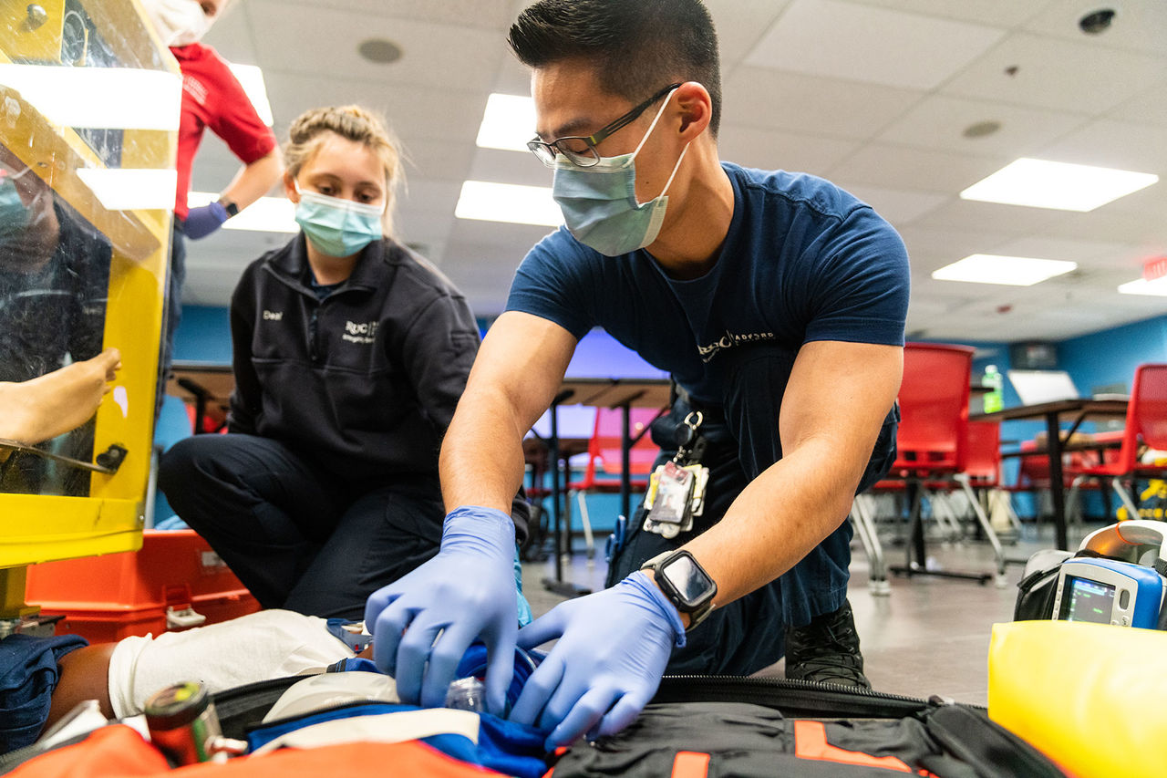 students in masks and gloves handling medical equipment