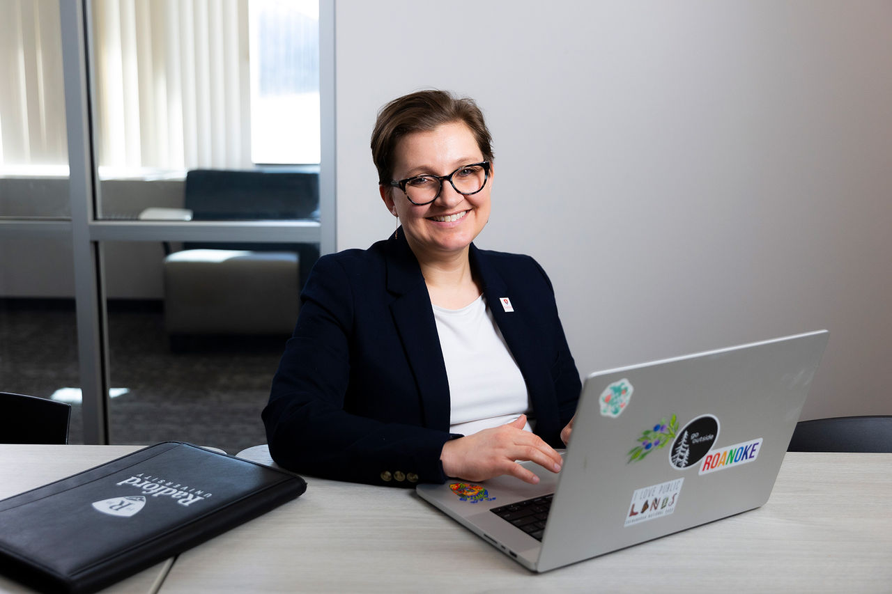 Rachel Rogers on a laptop, smiling at the camera