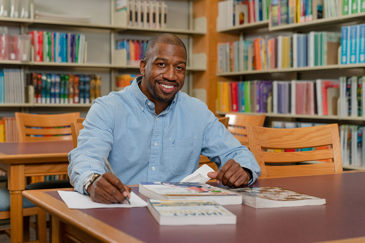 male sitting at a table in a library