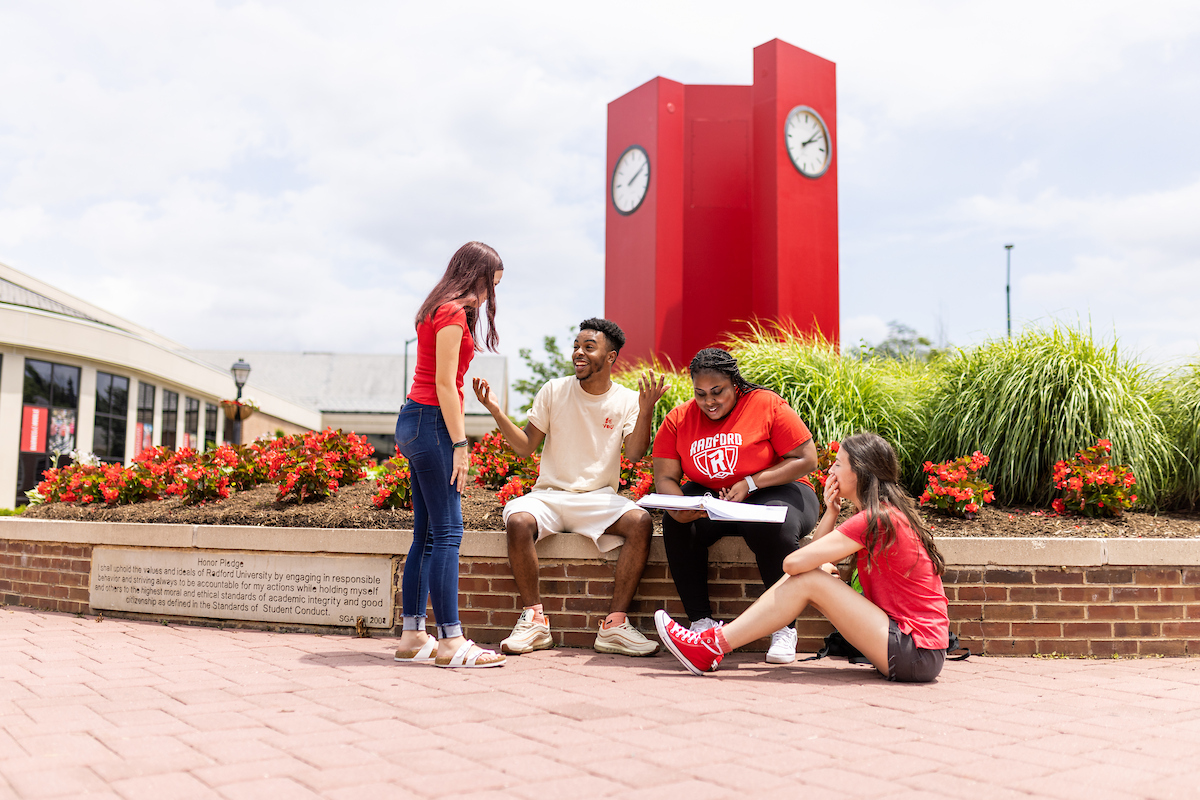 Three students smiling in front of Heth clocks.